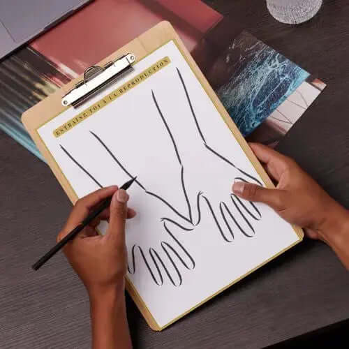 Pack henné complet : Cônes + Guide Digital sur une planche à dessins, avec des mains en esquisse.